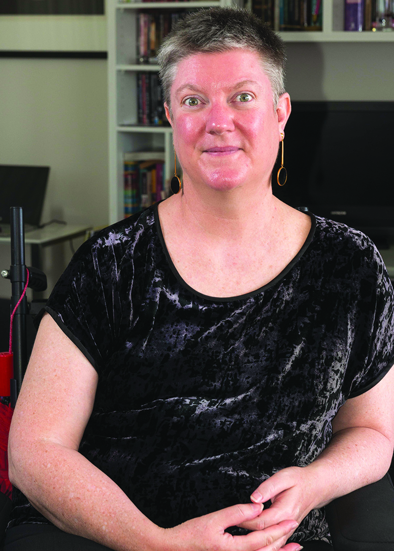 Portrait photo of Christina Ryan. Christina is wearing a black shirt and has short grey hair. The background is of an office. 