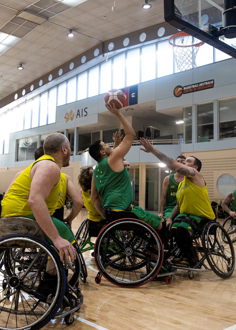 Men in green and gold Australian uniforms play wheelchair basketball