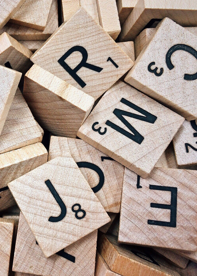 Wood scrabble tiles in a big pile with random letters showing.