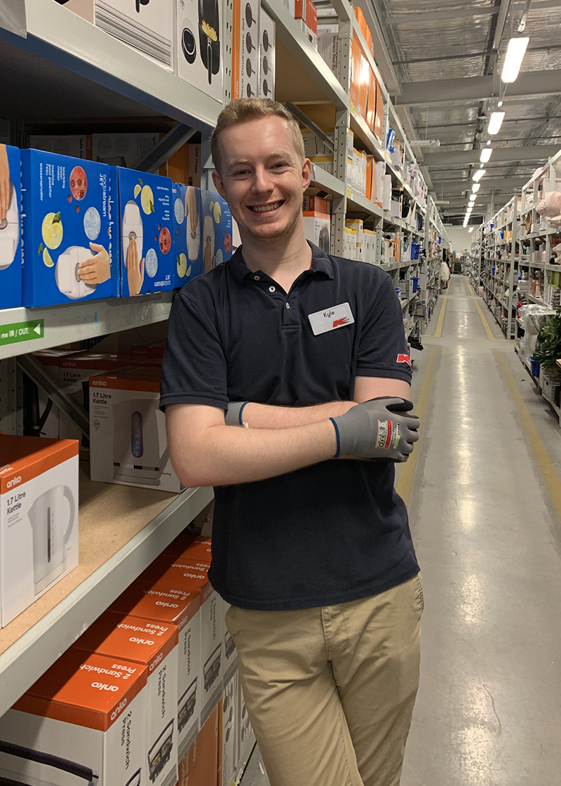 Kyle leaning against a row of shelves in the Kmart storeroom