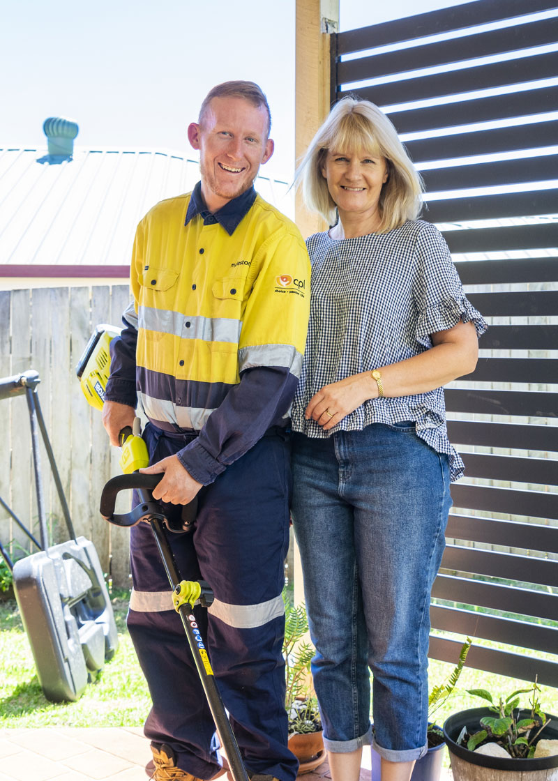 A man and a woman standing next to each other smiling at the camera. He is wearing a high vis uniform.