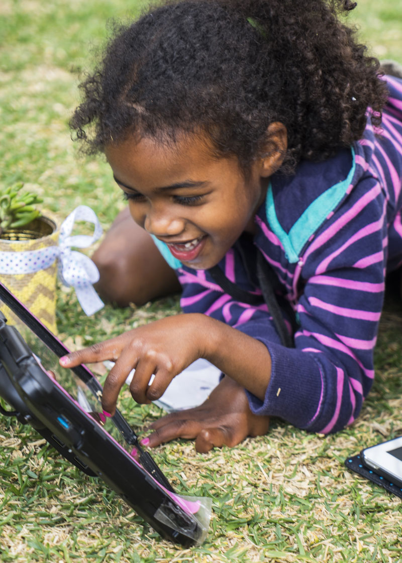 Girl laying on the grass using a communication device