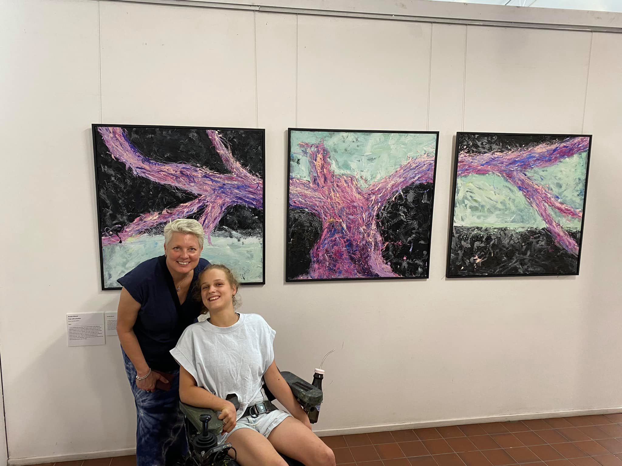 Annika and another person in front of three of her artworks hung on a wall in a gallery