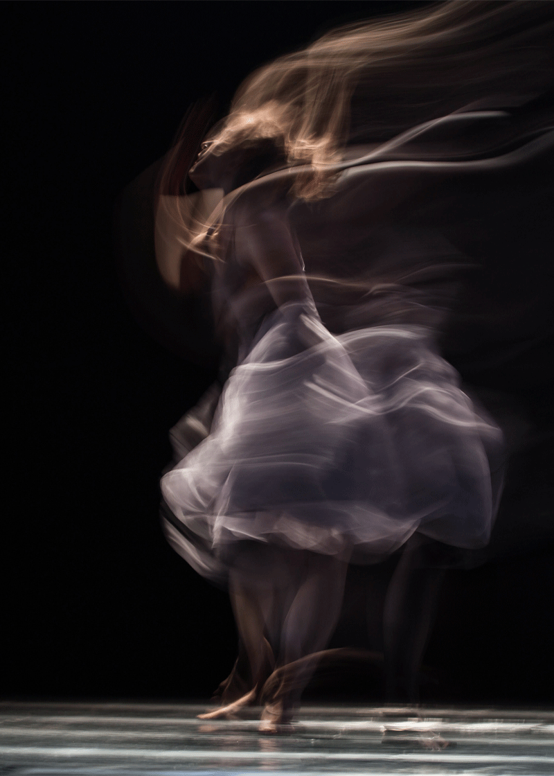 A blurry image of a person dancing with a black background