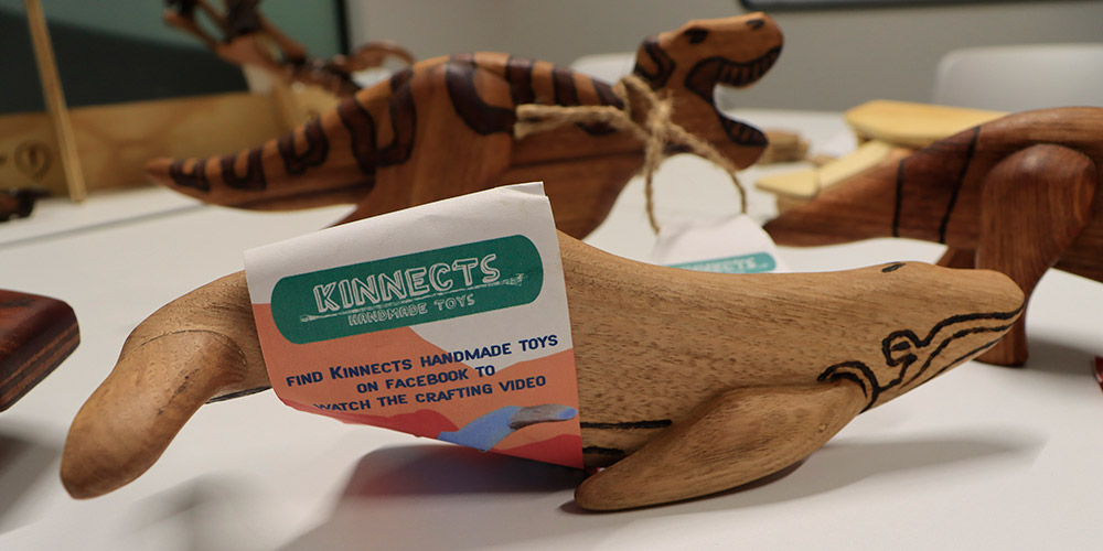 A whale toy shaped out of timber with a Kinnect tag attached.